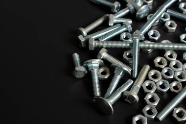 Siyah arkaplana karşı birçok metal cıvata ve fındık