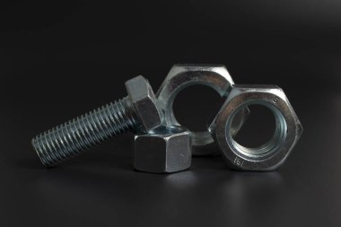 siyah arkaplana karşı birkaç büyük metal cıvata ve fındık