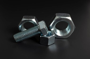 siyah arkaplana karşı birkaç büyük metal cıvata ve fındık