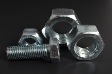 siyah arkaplana karşı birkaç büyük metal cıvata ve fındık