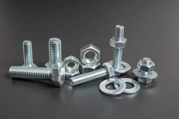 siyah arkaplana karşı birkaç metal cıvata ve fındık