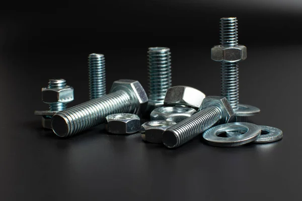 siyah arkaplana karşı birkaç metal cıvata ve fındık