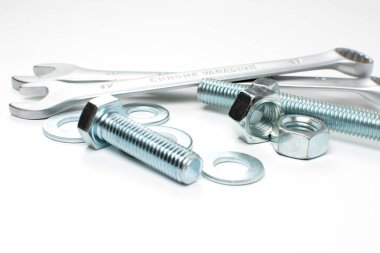 Beyaz arka planda gümüş metal cıvatalar, fındıklar ve anahtarlar