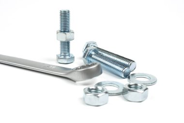 Beyaz arka planda gümüş metal cıvatalar, fındıklar ve anahtarlar