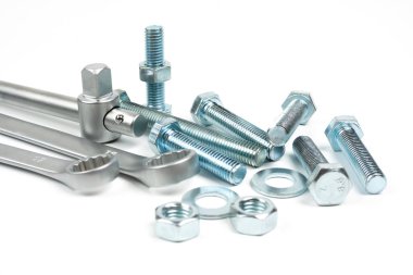 Beyaz arka planda gümüş metal cıvatalar, fındıklar ve anahtarlar