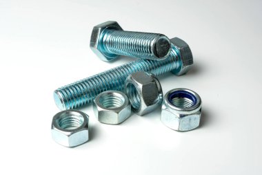 beyaz arkaplanda hafif metalden yapılmış cıvata ve fındık grubu