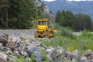Bir dağ nehrinin kıyısında ağır inşaat makineleri