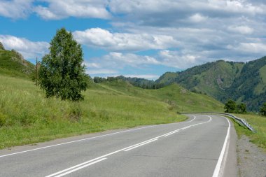 Otoyol ve dağ zirveleri bulutlu mavi gökyüzünün arka planında