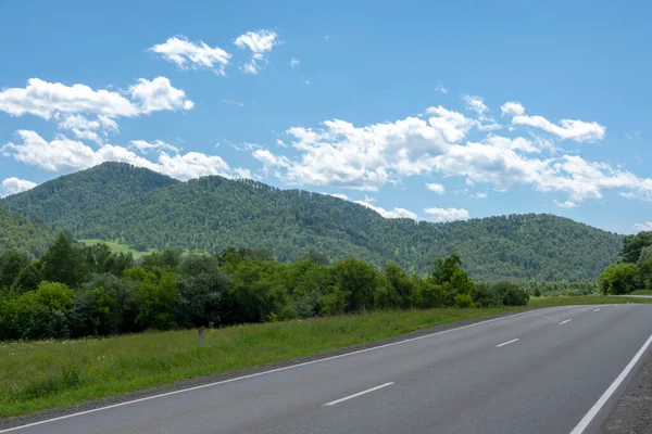 Otoyol ve dağ zirveleri bulutlu mavi gökyüzünün arka planında