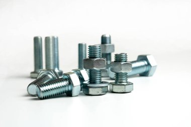 Beyaz arka planda birkaç metal cıvata ve fındık var.