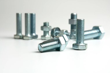Beyaz arka planda birkaç metal cıvata ve fındık var.