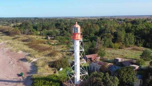 Una órbita aérea girando alrededor del faro de Pape. Un viejo faro rojo. Fondo azul marino — Vídeos de Stock