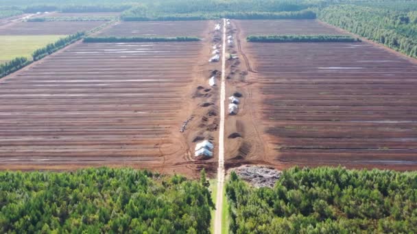 Luchtfoto vliegend langs de weg over turf oogstveld. Turfwinning. Stapels turf. — Stockvideo