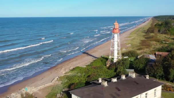 Drehschuss aus der Luft um den Leuchtturm Pape. Alter roter Leuchtturm. Blauer Meereshintergrund — Stockvideo