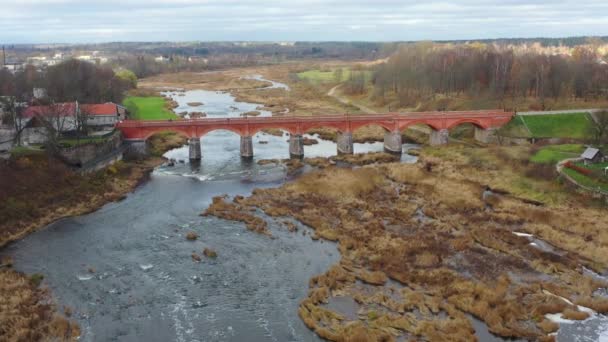 Luchtfoto die richting The Old Brick Bridge vliegt over de Venta rivier in Kuldiga — Stockvideo