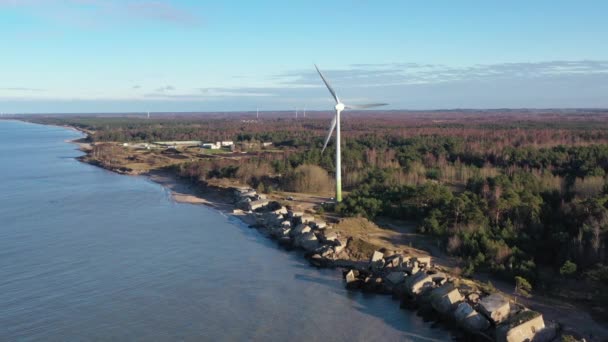 Tiro aéreo voando em direção a Liepaja Northern Forts, antigas fortificações abandonadas na costa do mar Báltico, na Letônia. Grande turbina eólica — Vídeo de Stock