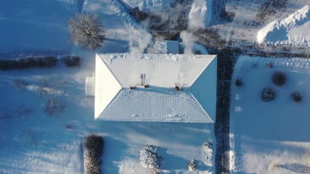 Vista aérea de arriba hacia abajo del techo de una sola casa con chimenea humeante en invierno — Vídeos de Stock