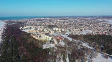 Karla kaplı Liepaja şehrine doğru uçan hava manzarası