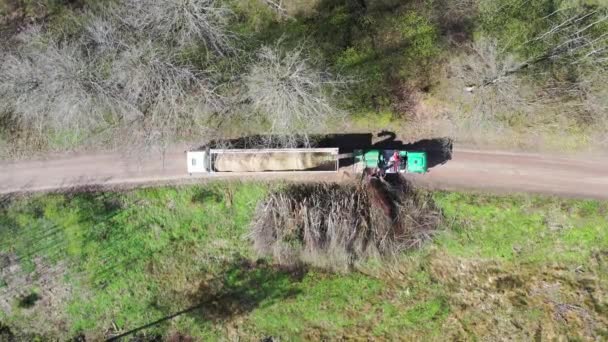 Aerial top down view of wood chipper blowing shredded wood into back of a truck. Forest background — Stock Video