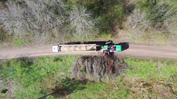 Vista aérea de arriba hacia abajo de la astilladora de madera que sopla madera triturada en la parte posterior de un camión. Fondo forestal — Vídeo de stock