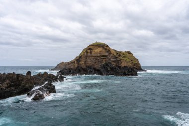 Waves crashing against black rocks in Porto Moniz in Madeira, Portugal