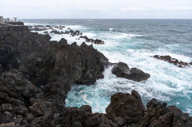 Waves crashing against black rocks in Porto Moniz in Madeira, Portugal