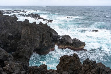 Waves crashing against black rocks in Porto Moniz in Madeira, Portugal