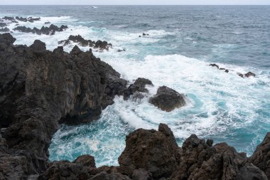 Waves crashing against black rocks in Porto Moniz in Madeira, Portugal