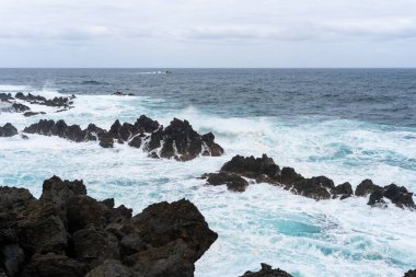 Waves crashing against black rocks in Porto Moniz in Madeira, Portugal