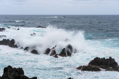 Waves crashing against black rocks in Porto Moniz in Madeira, Portugal