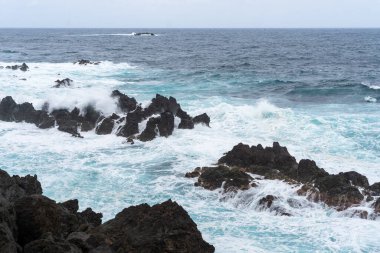 Waves crashing against black rocks in Porto Moniz in Madeira, Portugal