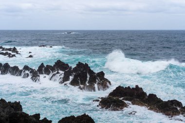 Waves crashing against black rocks in Porto Moniz in Madeira, Portugal