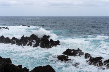Waves crashing against black rocks in Porto Moniz in Madeira, Portugal