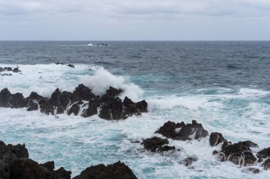 Waves crashing against black rocks in Porto Moniz in Madeira, Portugal