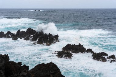 Waves crashing against black rocks in Porto Moniz in Madeira, Portugal
