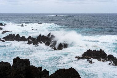 Waves crashing against black rocks in Porto Moniz in Madeira, Portugal
