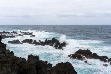 Waves crashing against black rocks in Porto Moniz in Madeira, Portugal