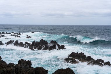 Waves crashing against black rocks in Porto Moniz in Madeira, Portugal