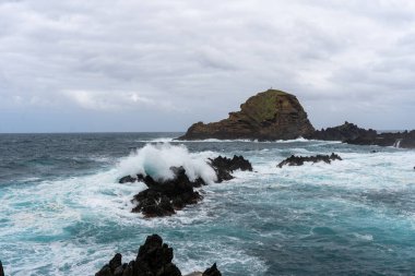 Waves crashing against black rocks in Porto Moniz in Madeira, Portugal