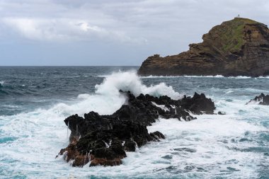Waves crashing against black rocks in Porto Moniz in Madeira, Portugal