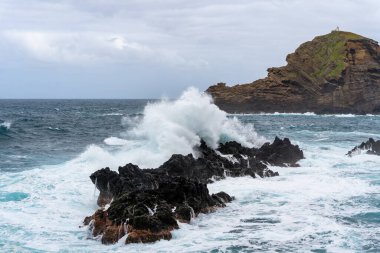 Waves crashing against black rocks in Porto Moniz in Madeira, Portugal