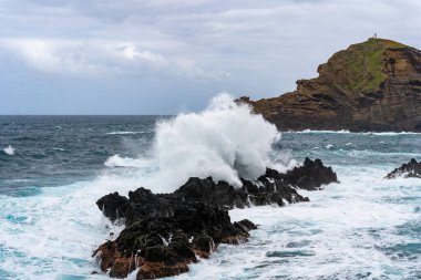 Waves crashing against black rocks in Porto Moniz in Madeira, Portugal