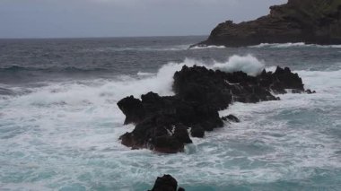 Portekiz, Madeira 'daki Porto Moniz' de siyah kayalara vuran dalgaların yavaş hareketi