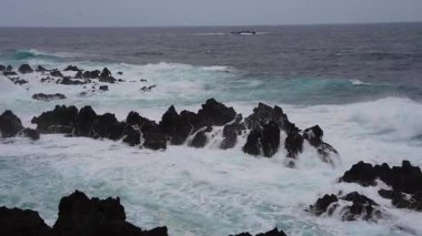Waves crashing against black rocks in Porto Moniz in Madeira, Portugal