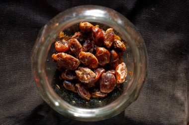 Cam bir kavanozda koyu arka planda lezzetli kurutulmuş hurmalar.