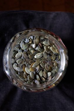 Cam bir kavanozdaki kabak tohumları koyu arka planda