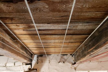 Tahta kirişlerin ve tahtaların altında bir tavan arası.