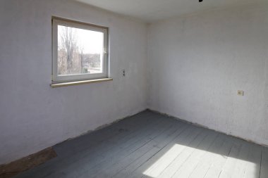 Tamirat sırasında stüdyonun boş beyaz odası. Döşeme tahtaları birinci kat boyalıdır..