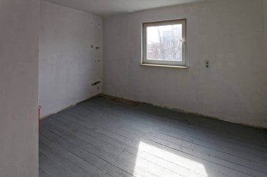 Tamirat sırasında stüdyonun boş beyaz odası. Döşeme tahtaları birinci kat boyalıdır..