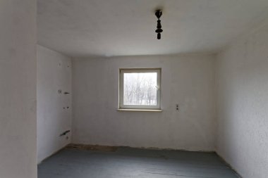 Tamirat sırasında stüdyonun boş beyaz odası. Döşeme tahtaları birinci kat boyalıdır..